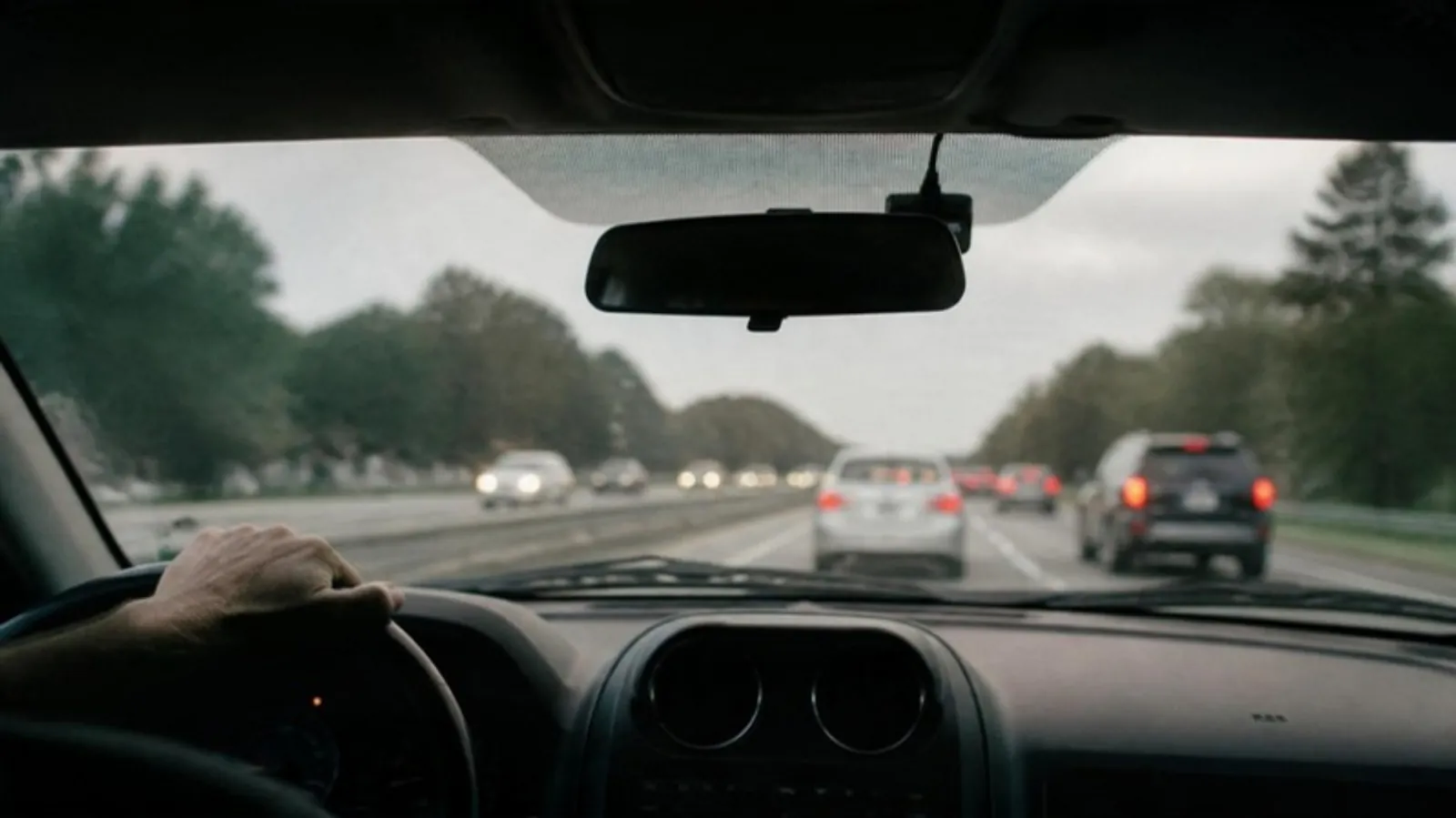 Small dash cam tucked behind a rear-view mirror with a clear view of the highway