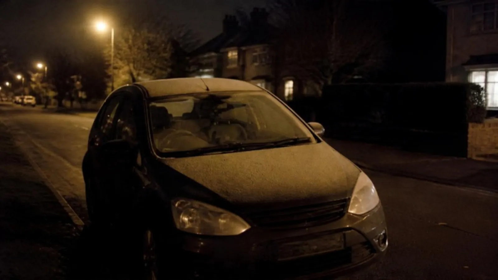 Hatchback parked on a residential street at night with a dash cam light glowing behind the windshield