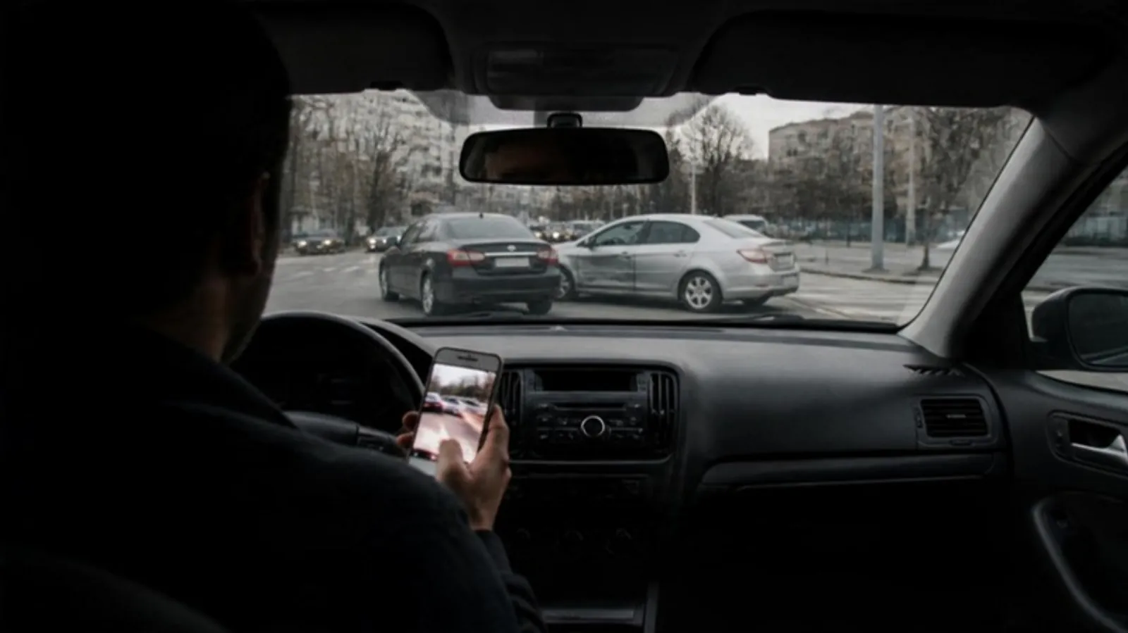 Driver in a parked car holding a phone with road video after a minor collision ahead